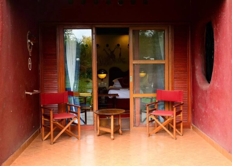 A room's terrace between two red walls, with two red folding chairs and a round table