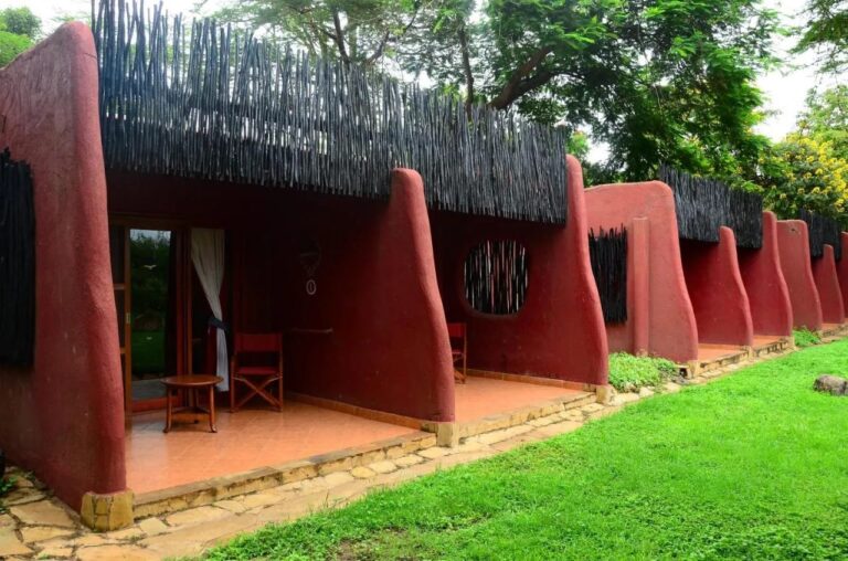 The room terraces of Amboseli Serena Safari Lodge, between curved red walls, facing a lawn