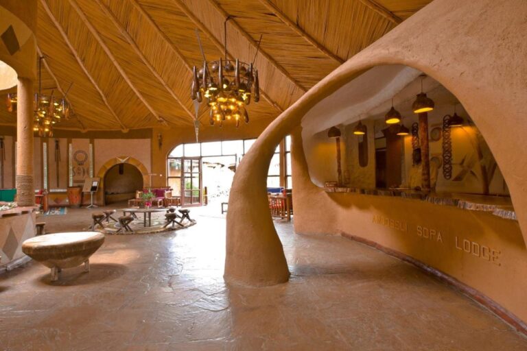 The carved earthen reception counter, engraved with the name of Amboseli Sopa Lodge, under a reed ceiling
