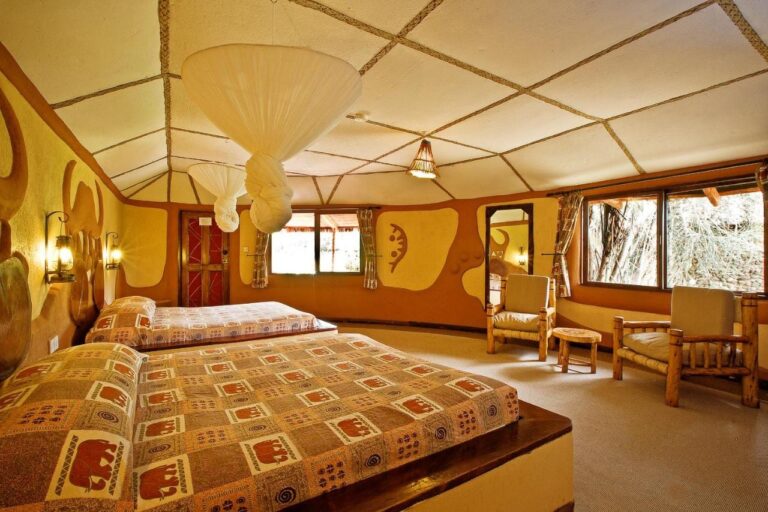 A twin room with elephant-patterned bedspreads, under mosquito nets knotted to the ceiling