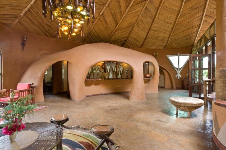 The lobby with earthen walls carved into arches, under a reed ceiling and a chandelier