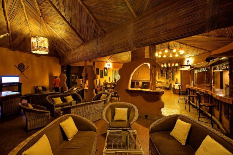 The lounge and bar, with rattan armchairs with yellow cushions and stools at the counter