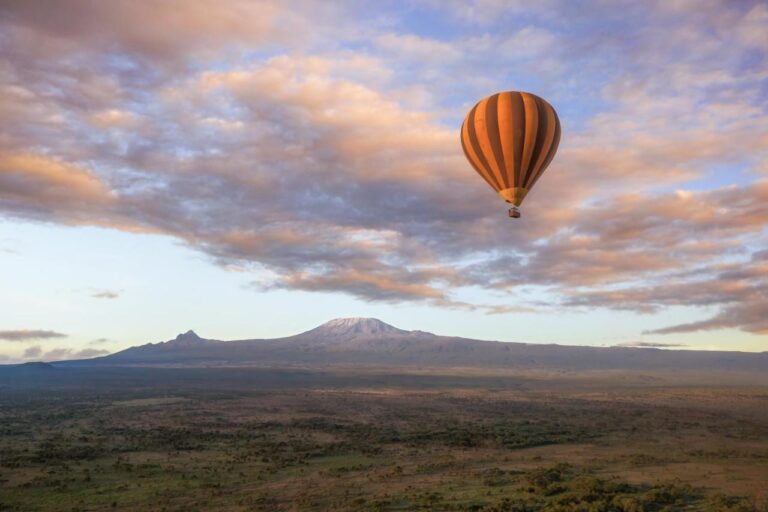 A hot-air balloon above the plain, with Kilimanjaro on the horizon under a pink sky