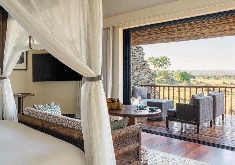 A room opening onto its terrace and the savanna, seen from the four-poster bed