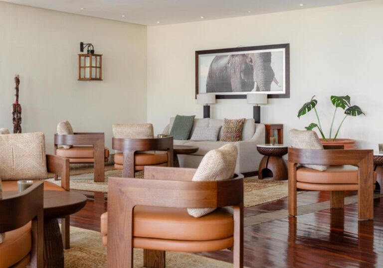 A lounge with tan leather armchairs, under a large portrait of an elephant