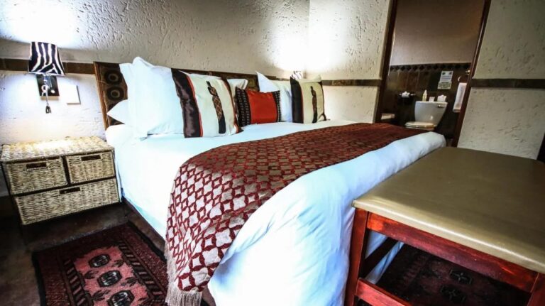 A double bed with a red and white throw, next to a nightstand with wicker baskets