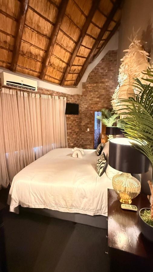 A room under the thatch, with a brick wall, an air conditioner and a lamp with a gold base