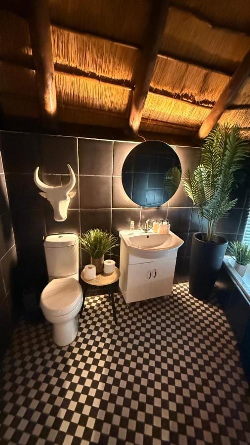 A bathroom with a black and white checkerboard floor, a round mirror and a white bull's head on the wall