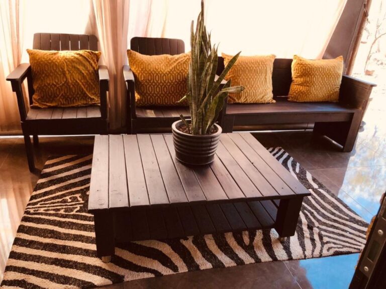 A lounge with dark wood seats, mustard yellow cushions and a coffee table on a zebra-print rug