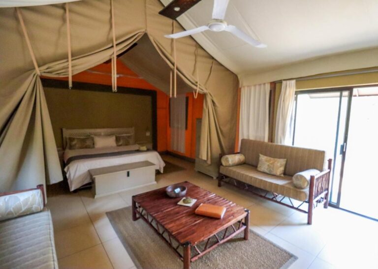 Inside a tent, with a double bed, a sofa, a wooden coffee table and a picture window