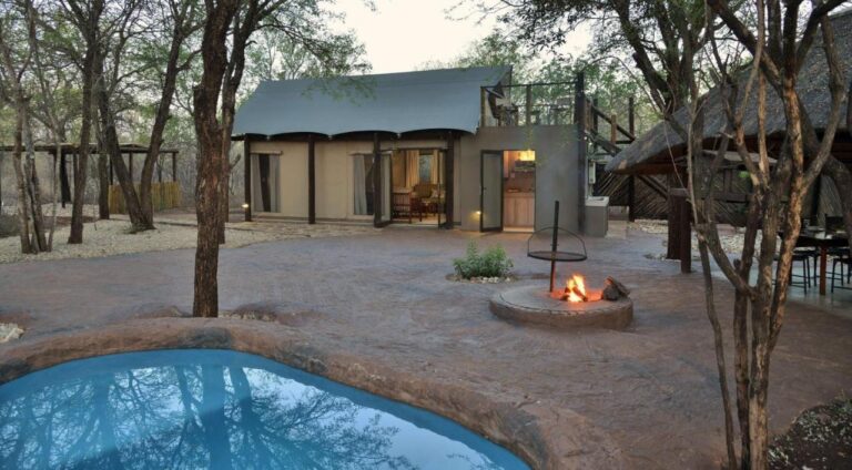 A private pool and a fire burning in the fire pit, in front of a canvas-roofed tent