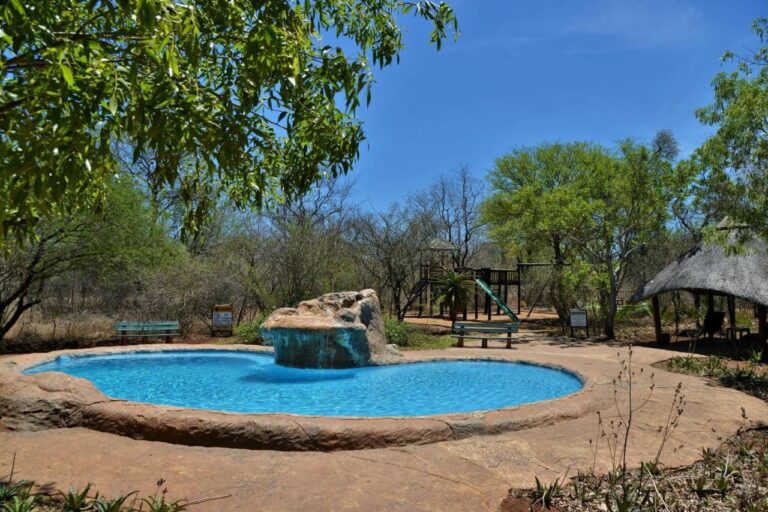 The waterfall pool at Jackalberry Ridge under a blue sky, surrounded by benches and trees
