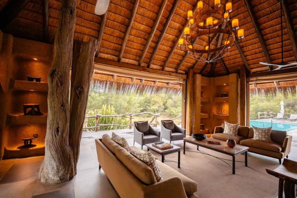 The lounge at Kapama River Lodge under a high thatched roof, opening onto a pool and the bush