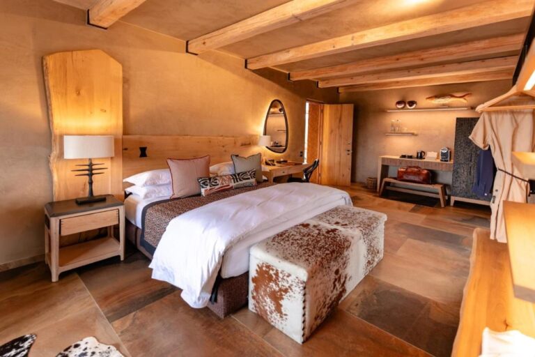 A suite with a double bed, a cowhide bench, a coffee corner and a hanging bathrobe