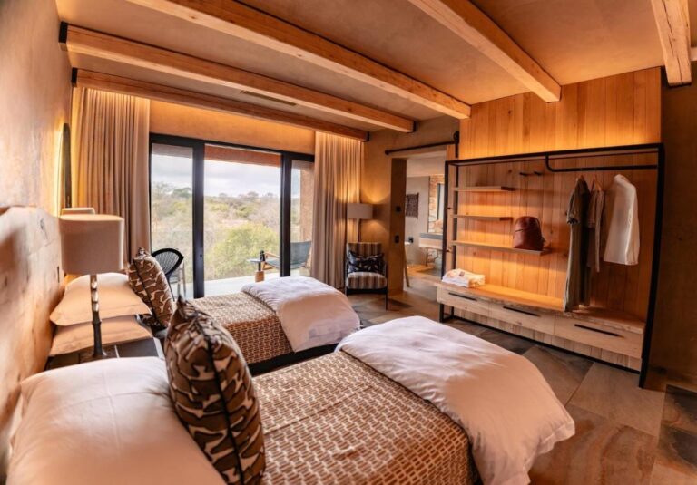 A suite with two beds, opening onto the bush through a picture window