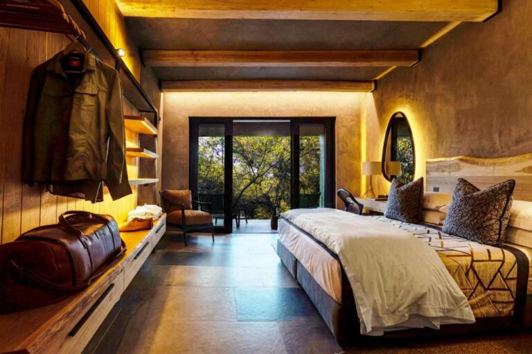 A suite with a double bed, opening onto a terrace among the trees