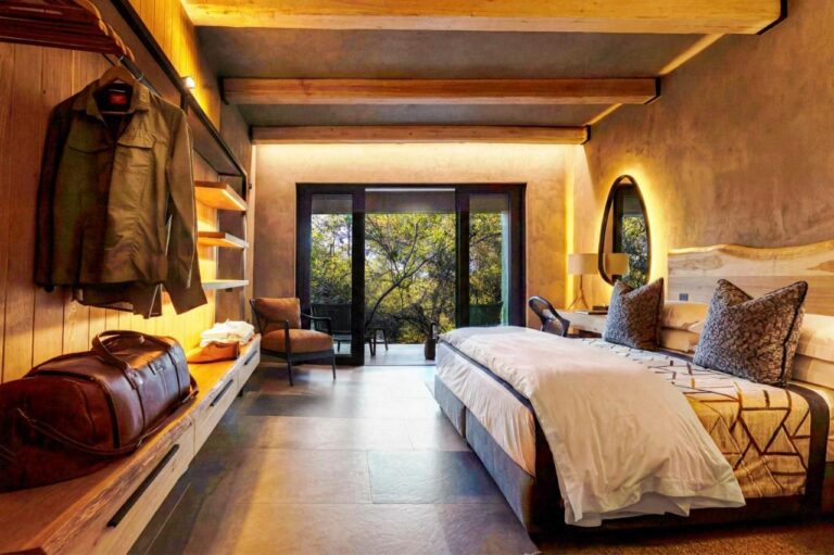 A hanging jacket and a travel bag in a suite, facing the double bed and the terrace