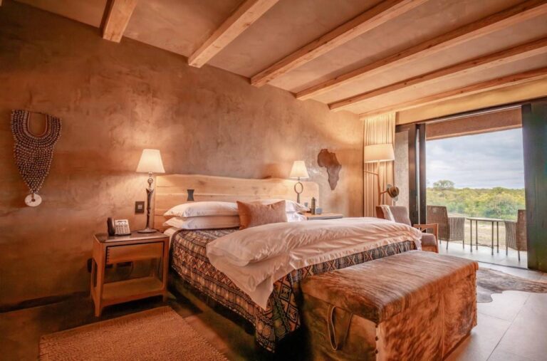 A suite with a double bed, a wooden map of Africa on the wall and a terrace over the bush