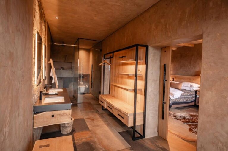 The bathroom of a suite, with a glass shower, a sink and an open wardrobe