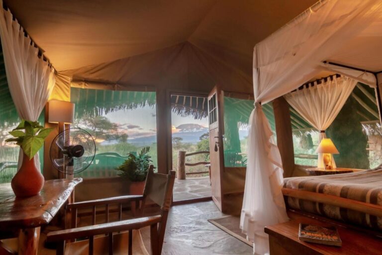 A Kibo Safari Camp tent open onto its terrace, with Kilimanjaro in the distance at dusk