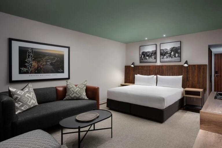 A Deluxe room with a double bed and a sofa, at Kruger Gate Hotel