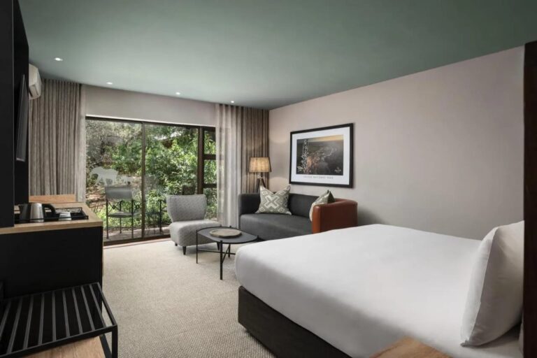 A Deluxe room with its balcony over the riverside vegetation
