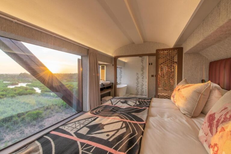 Inside a Kruger Shalati carriage, the bed facing a large window over the river and the bathtub at the far end
