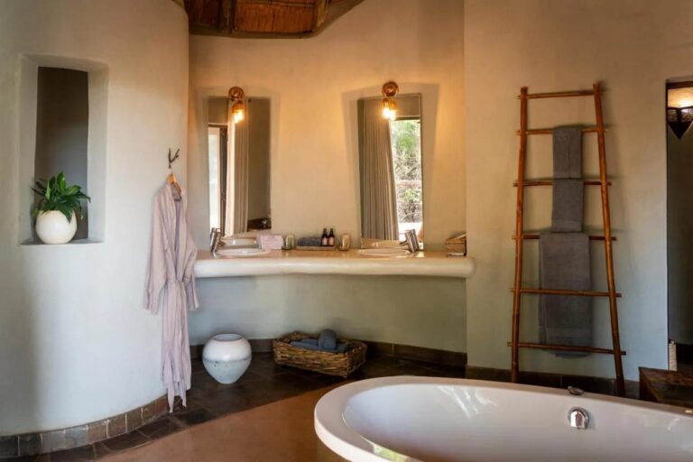 A bathroom with curved walls, a bathtub, two sinks and a towel ladder
