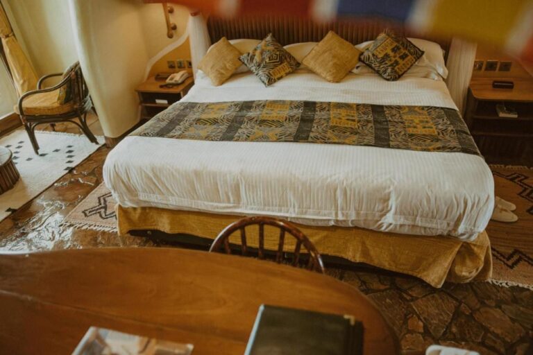A large bed seen from the desk, on a stone-tiled floor
