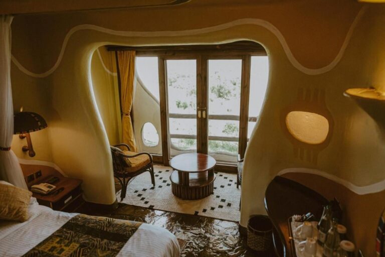 A room with curved walls at Mara Serena Safari Lodge, with a seating area in front of the French door to the balcony