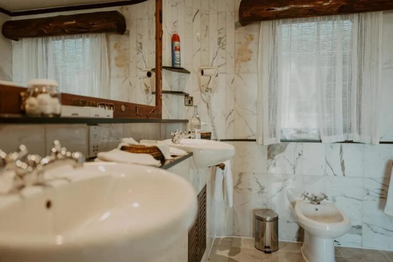 A close-up of a sink in a marble bathroom, with a bidet in the background