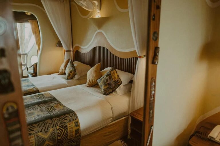 The two beds of a twin room, seen in a mirror with a carved wooden frame