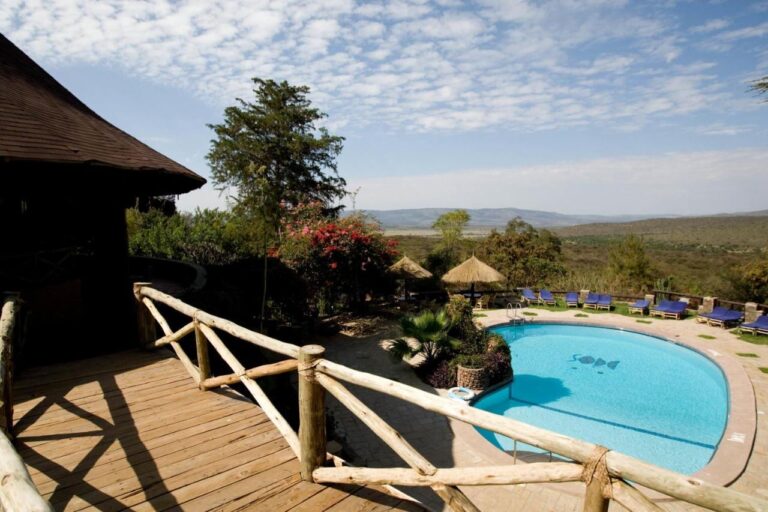 The pool at Mara Sopa Lodge seen from a wooden deck, facing the bush and the hills