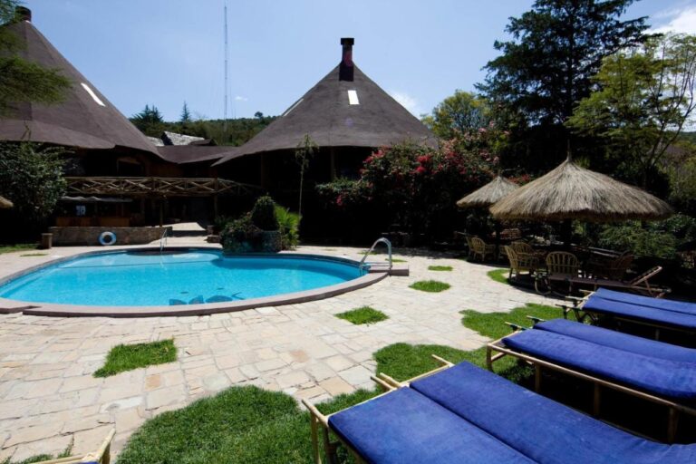 Sun loungers with blue cushions by the pool, near thatched umbrellas