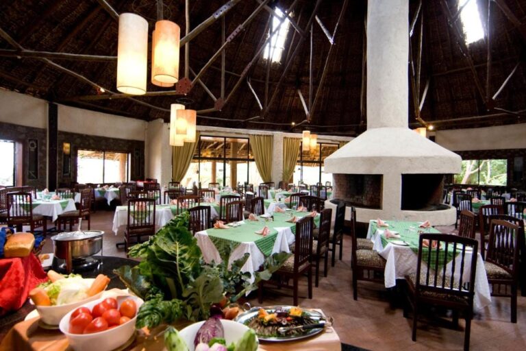 The restaurant, its tables with green tablecloths and a vegetable buffet in the foreground