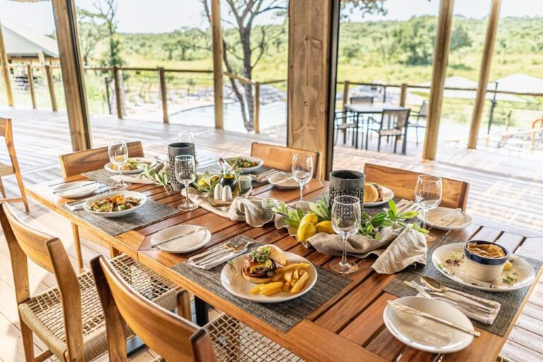 A table laid in the restaurant, open to the terrace, the pool and the bush