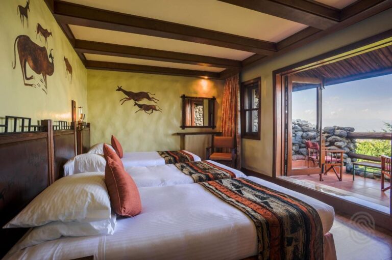 A room with three beds opening onto a stone-walled balcony