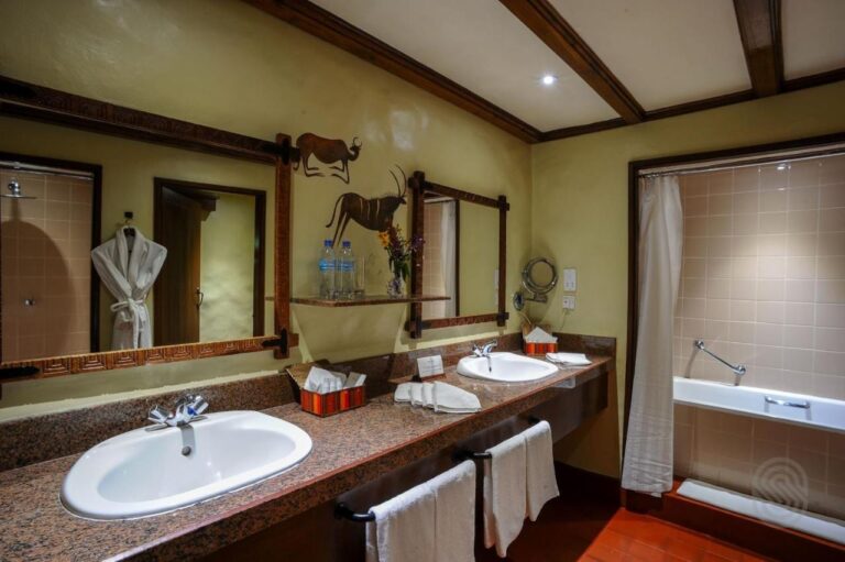 A bathroom with two sinks, a bathtub and a hanging bathrobe