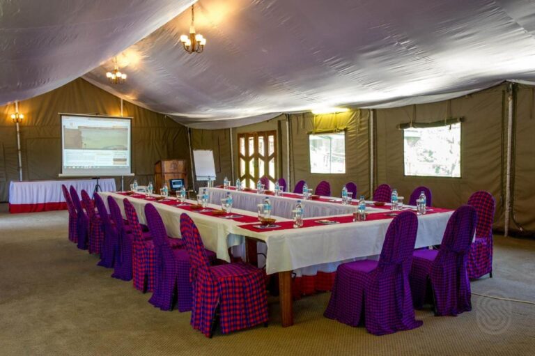 A meeting room under a tent, with a U-shaped table and chairs dressed in checked fabric