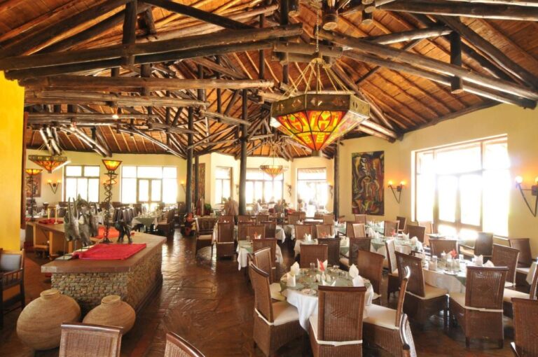 The restaurant under a log roof frame, with stained-glass chandeliers and white tablecloths