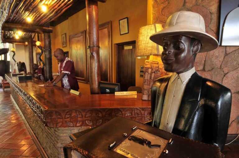 The reception, with a carved counter and a wooden statue of a man in a pith helmet
