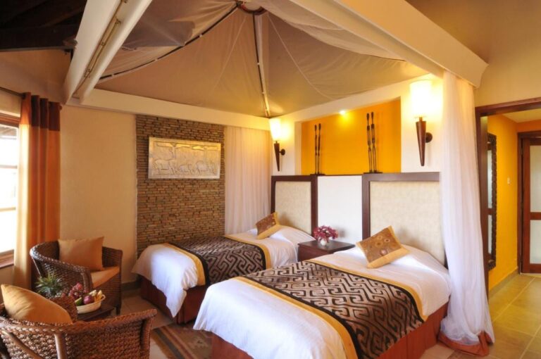 A twin room with rattan armchairs and a relief of elephants on a stone wall