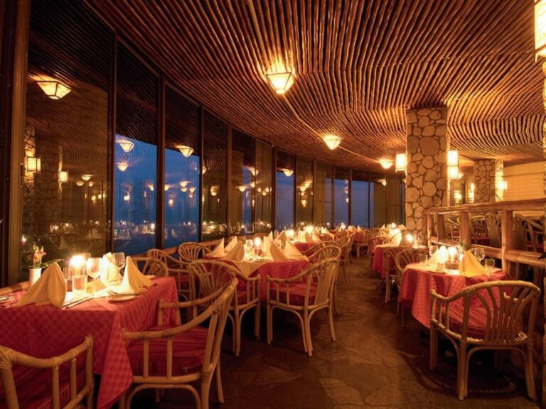 The candlelit restaurant, with its red tablecloths and rattan armchairs under a wooden ceiling