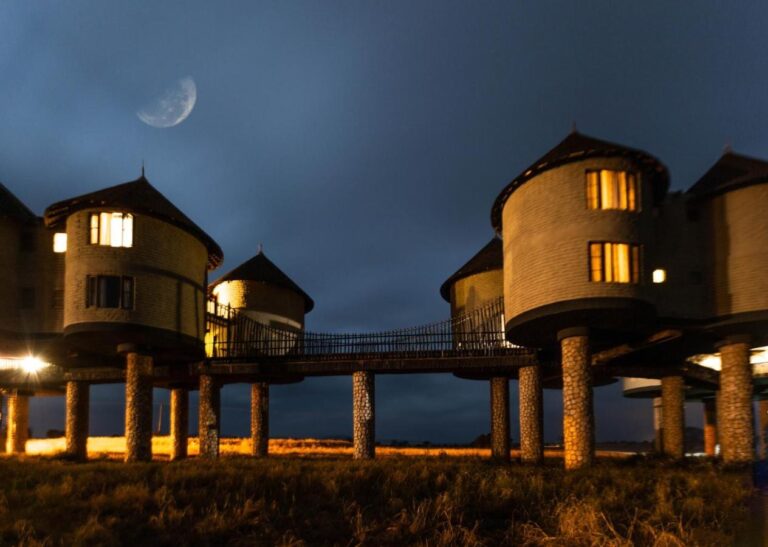 Two lit towers linked by a walkway, on their stone pillars, under the moon