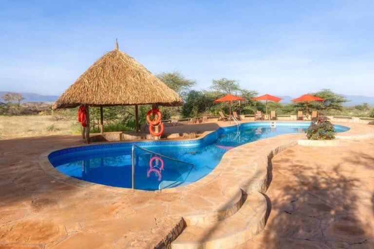 The pool at Samburu Sopa Lodge, its thatched shelter hung with orange life rings and its red umbrellas facing the bush