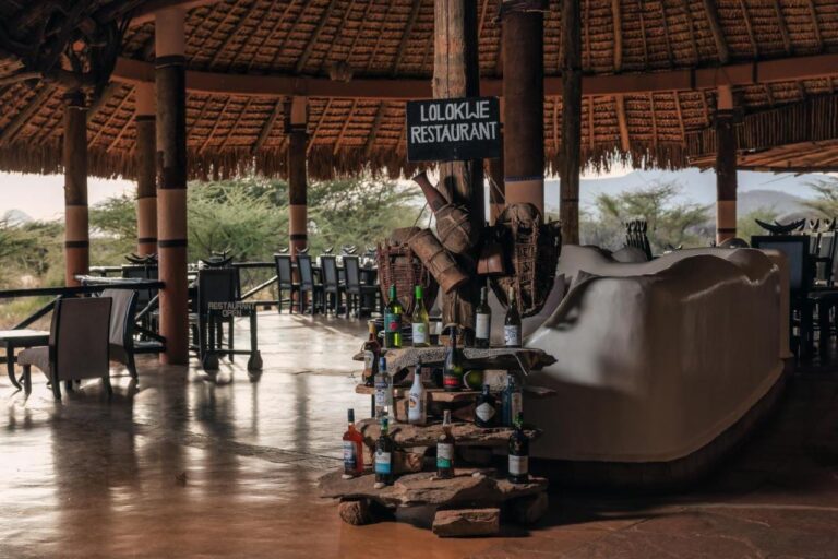The entrance to the Lolokwe restaurant, with wine bottles set on stones, under a large thatched roof
