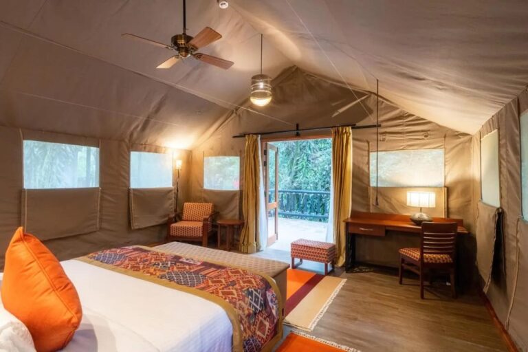 A tent with a desk, a ceiling fan and a door open onto the veranda