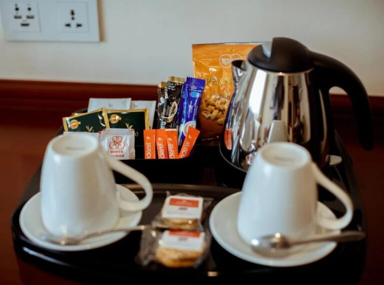 A tray with a kettle, two cups, tea, coffee sachets and cookies