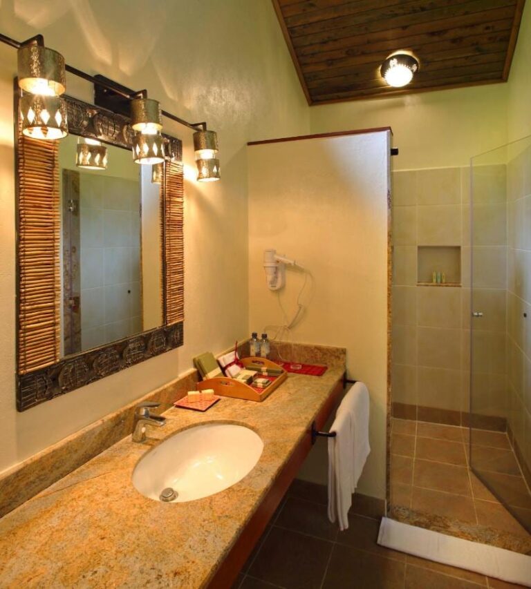 A bathroom with a granite vanity top, a hairdryer and a glass shower