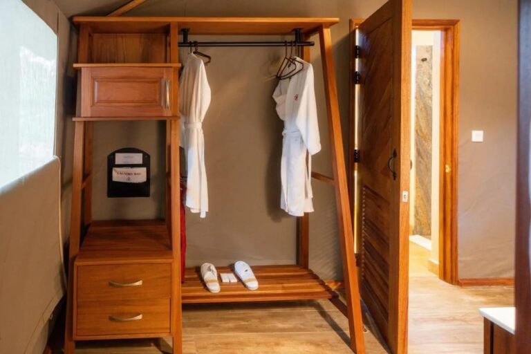 An open wardrobe with two bathrobes and slippers, near the bathroom door